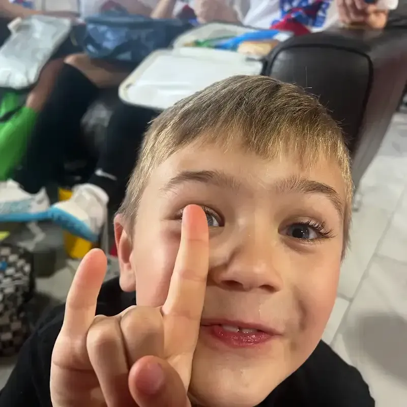 A young boy is making a peace sign with his fingers