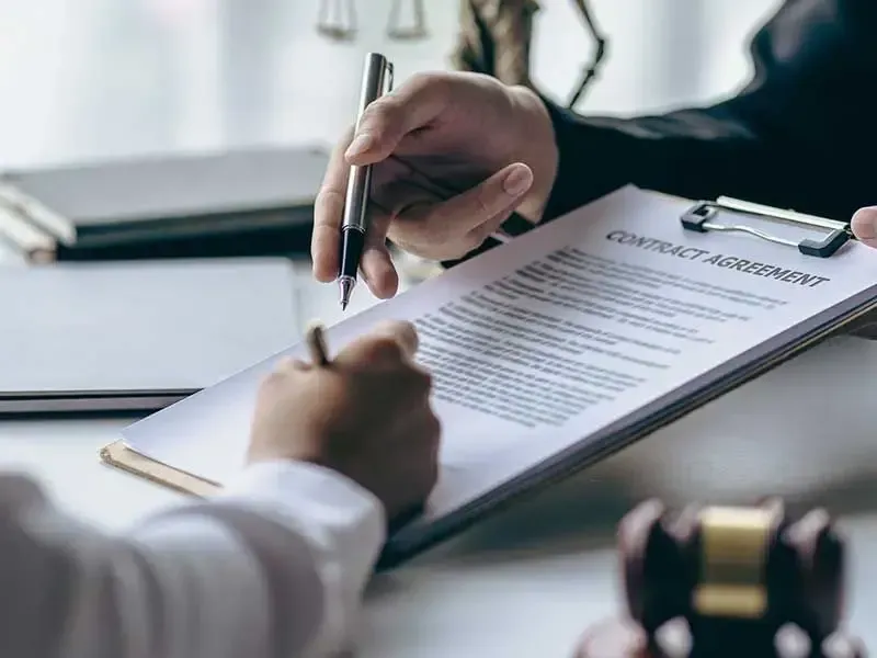 A person is signing a contract on a clipboard.