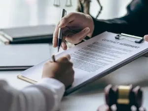 A person is signing a contract on a clipboard.