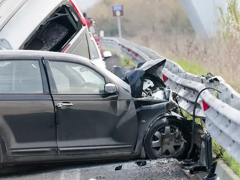 A car has crashed into a fence on the side of the road.