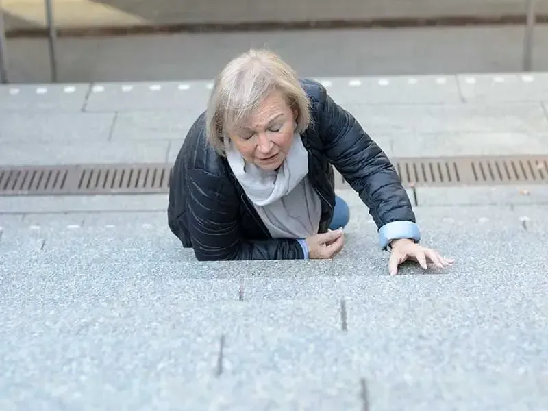 An elderly woman is falling down a set of stairs.