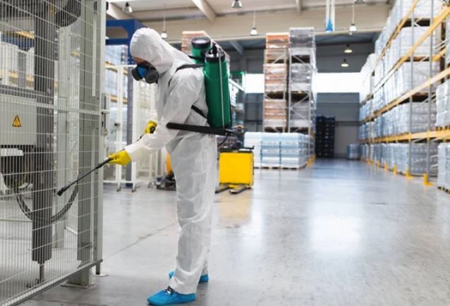 commercial exterminator spraying factory floor for pests