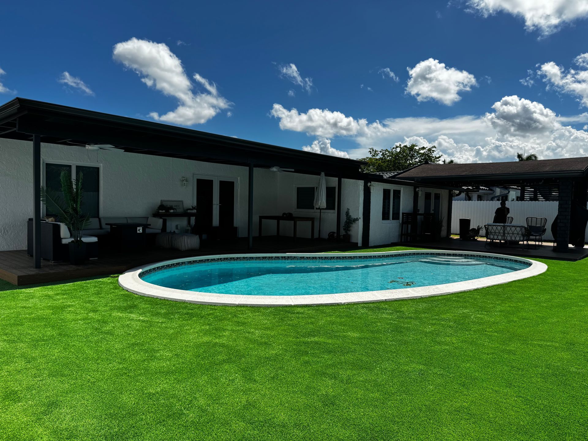 There is a large swimming pool in the backyard of a house.