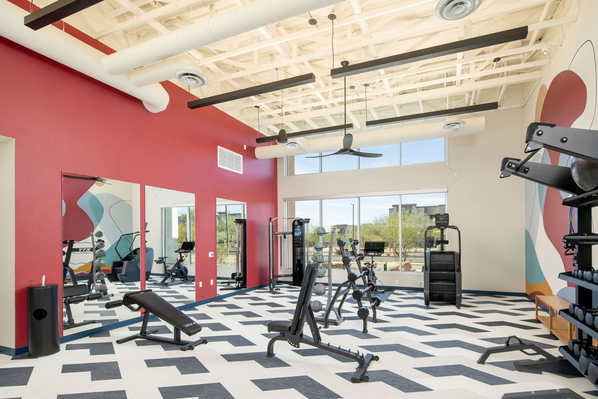 A gym with a lot of exercise equipment and a lot of mirrors.