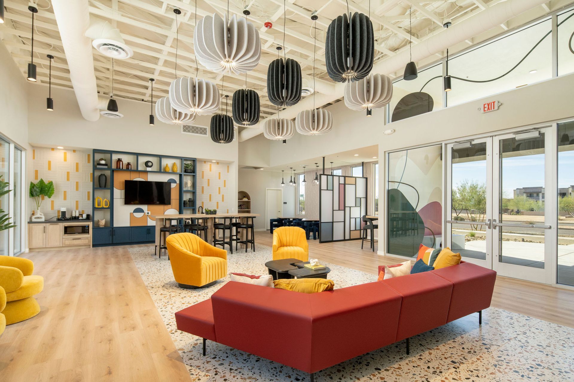 There is a large living room with a red couch and yellow chairs.