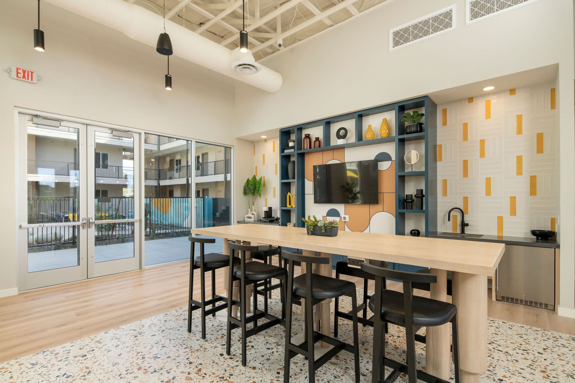 There is a long table with stools in the middle of the room.