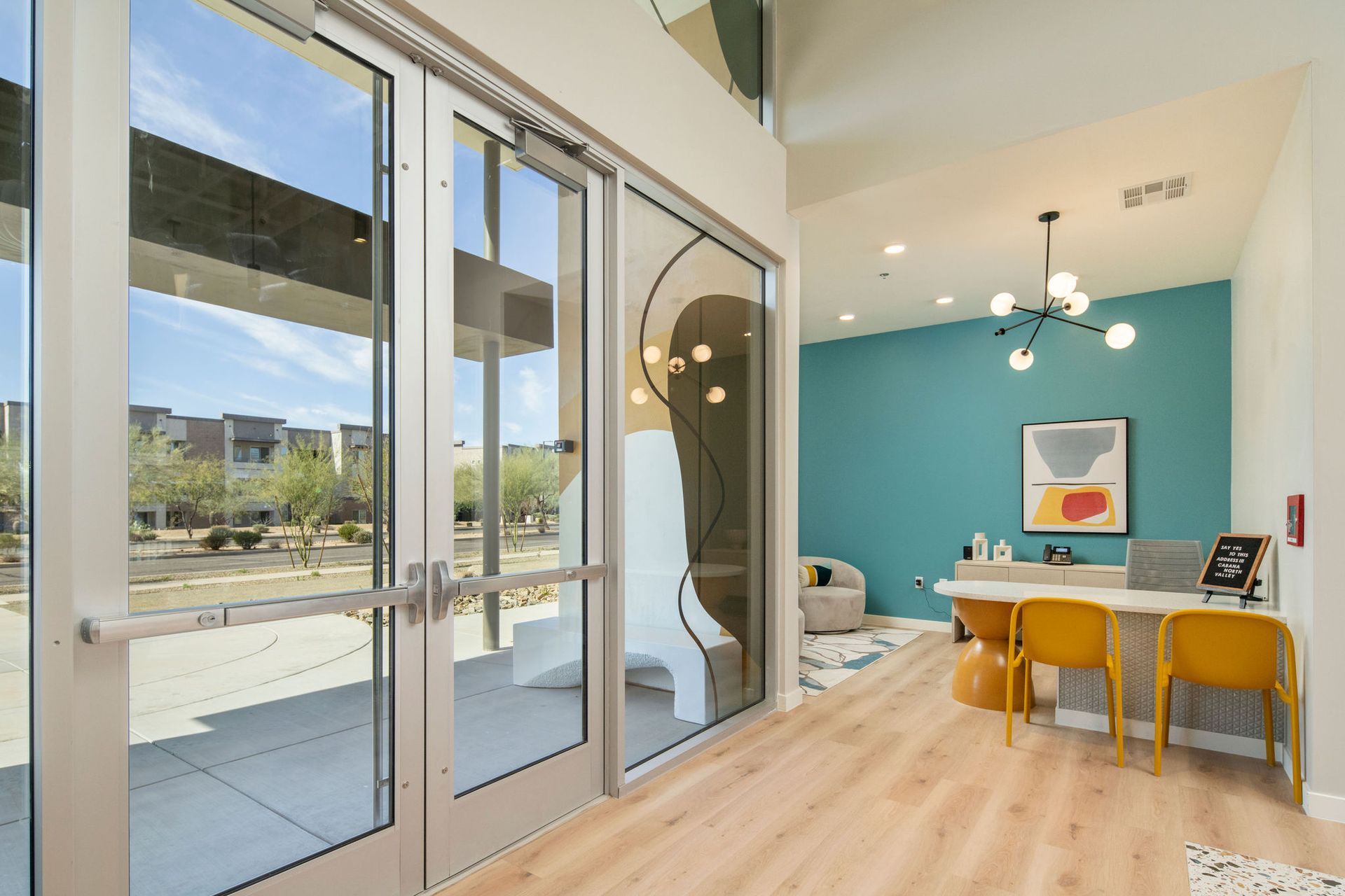 A room with a desk and chairs and a blue wall.