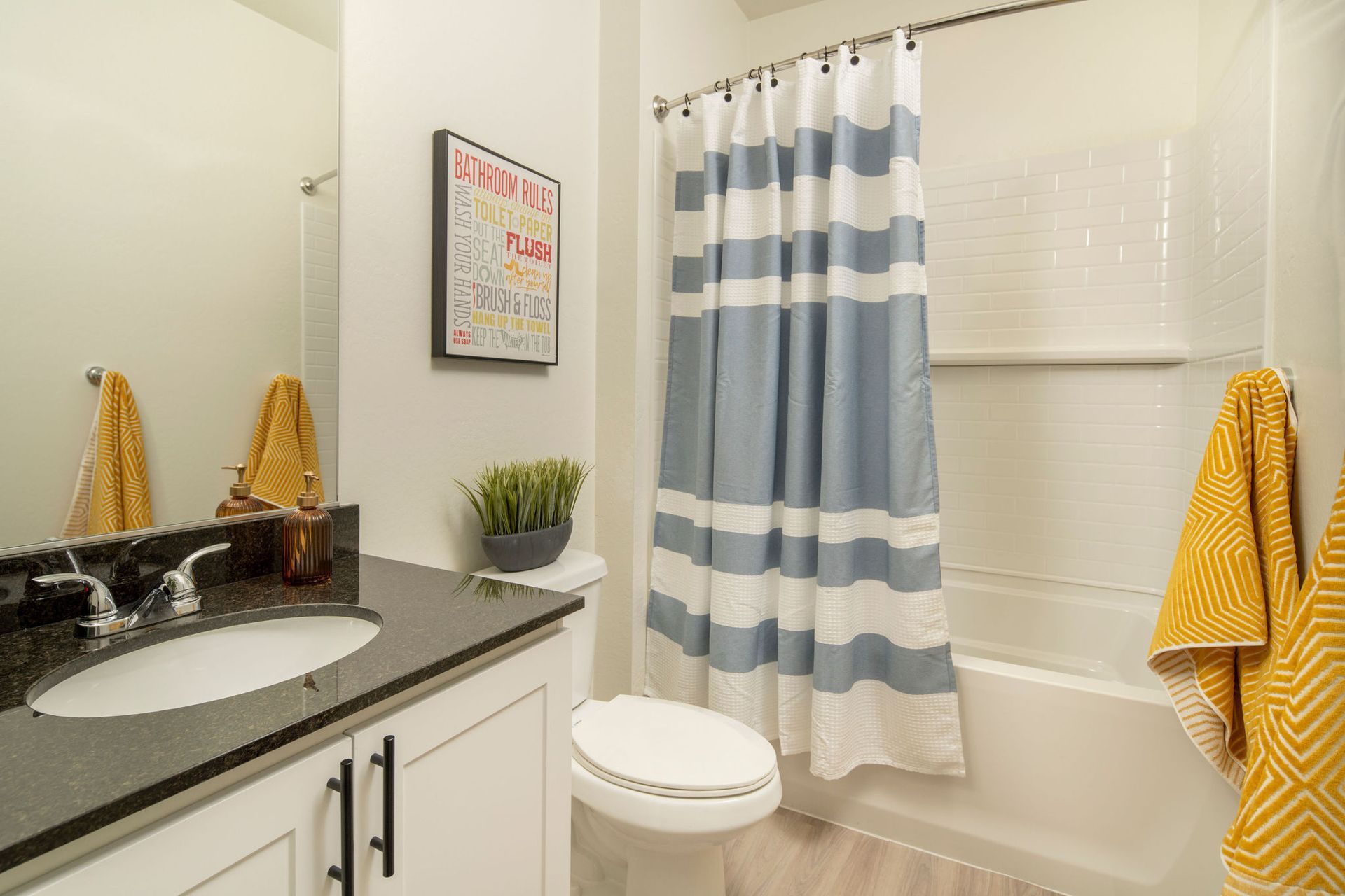 A bathroom with a sink , toilet , shower curtain and bathtub.