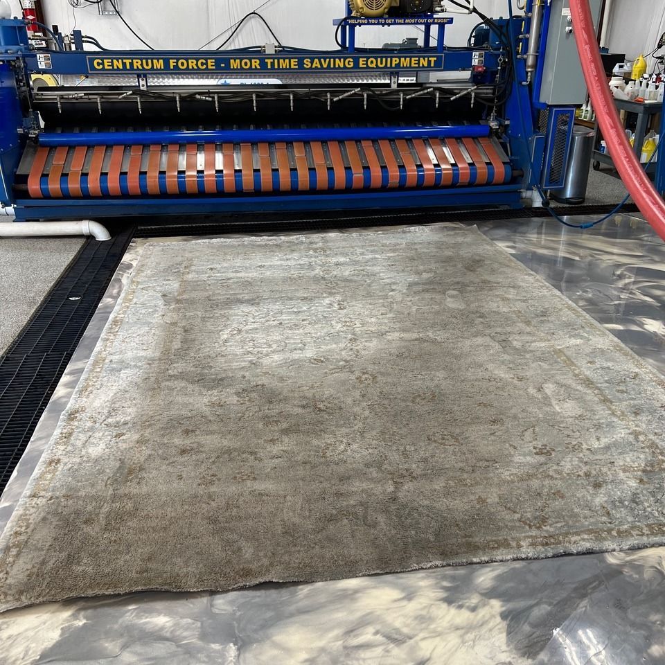 A gray rug on a floor in front of a Centrum Force industrial cleaning machine.