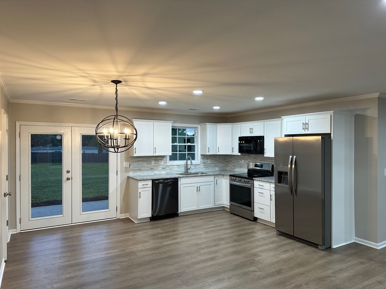 Modern kitchen with white cabinets, stainless steel appliances, a globe pendant light, and a set of glass paneled doors.