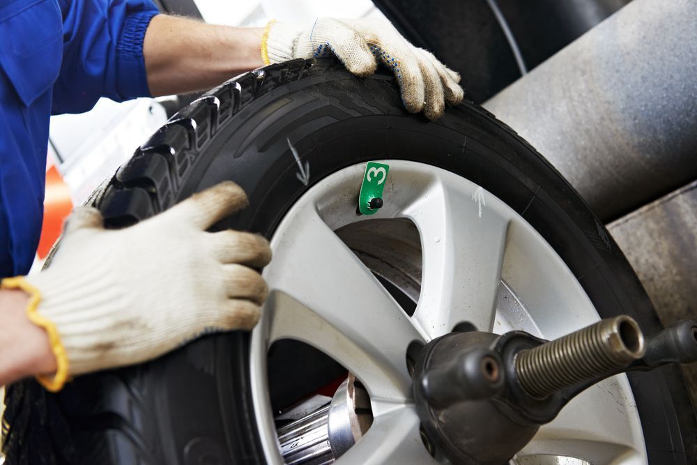 A Person in Work Gloves Adjusting a Car Tire on A Mounting Machine — Morisset Automotive in Morisset, NSW