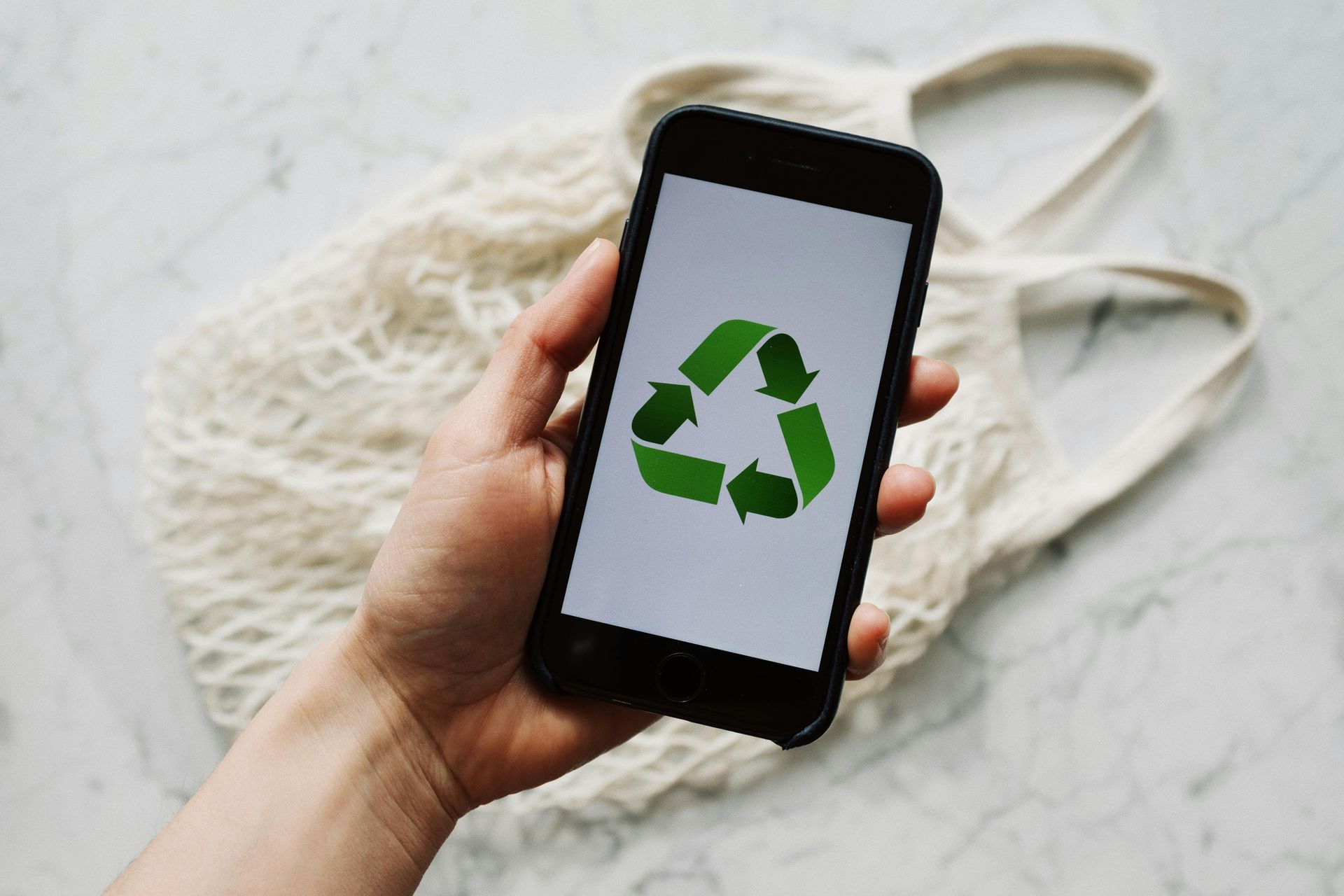 Uma pessoa está segurando um celular com um símbolo de reciclagem na tela.