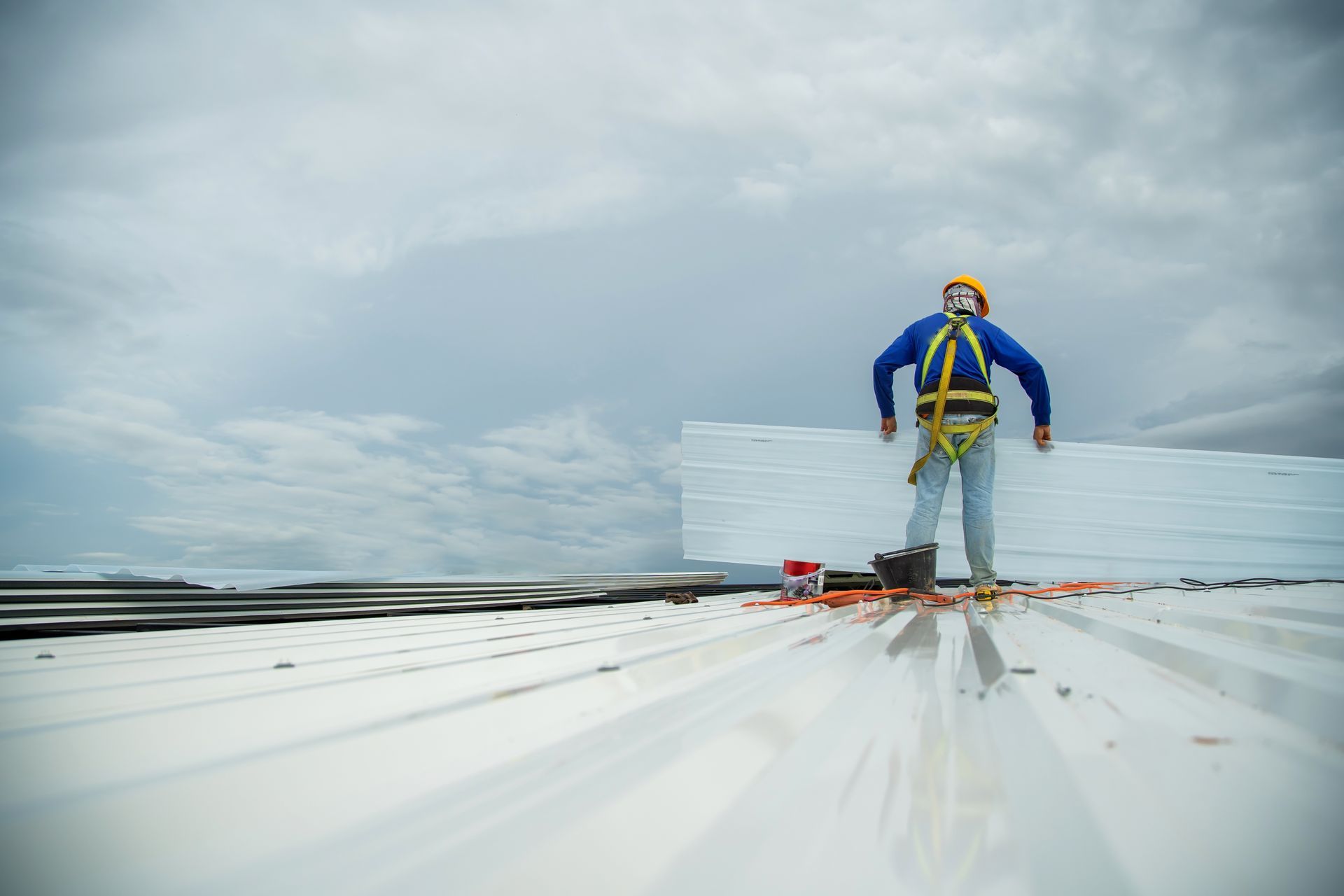 A commercial roof repair worker installing metal roofing panels.