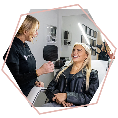 A woman is sitting in a chair looking at herself in a mirror.