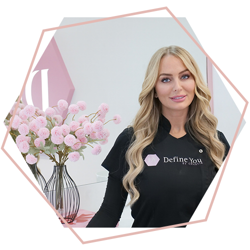 A woman is standing in front of a vase of pink flowers.