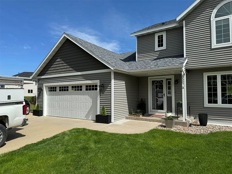 A large gray house with a white truck parked in front of it.