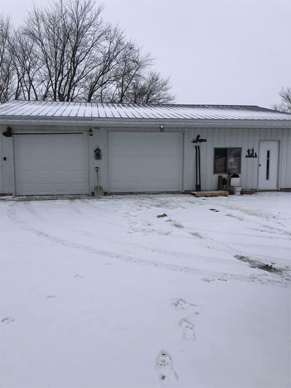 A white house with two garage doors is covered in snow.