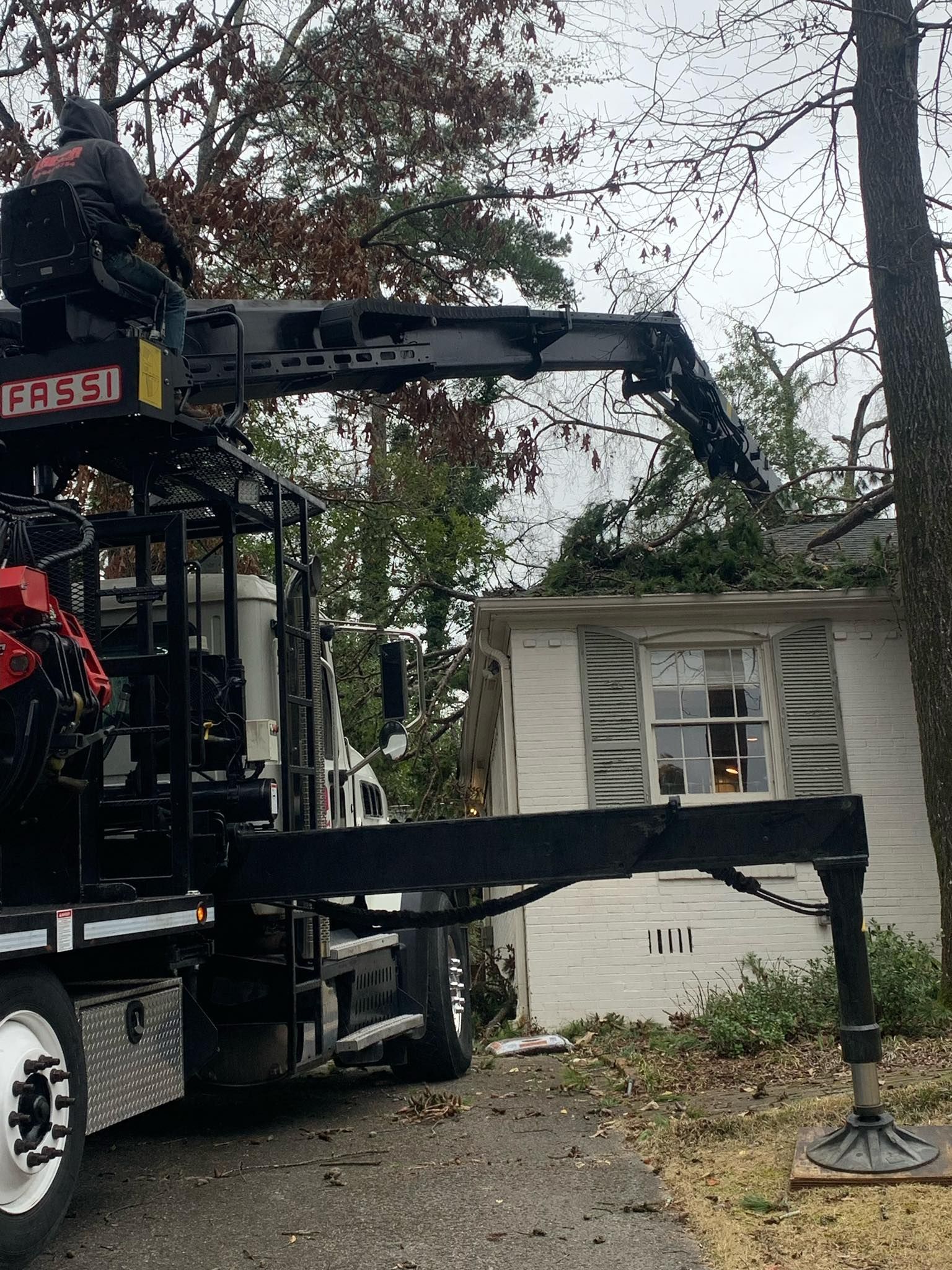 A truck with a crane attached to it is parked in front of a house. A truck with a crane attached to it is parked in front of a house.