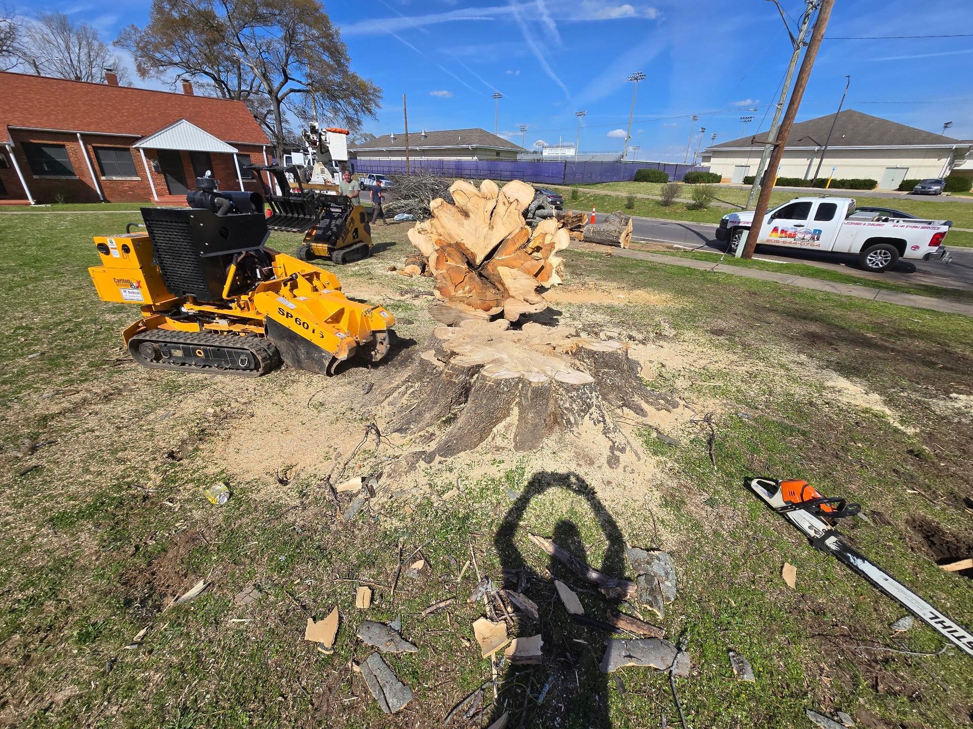 A large tree stump is being removed by an excavator. A large tree stump is being removed by an excavator.