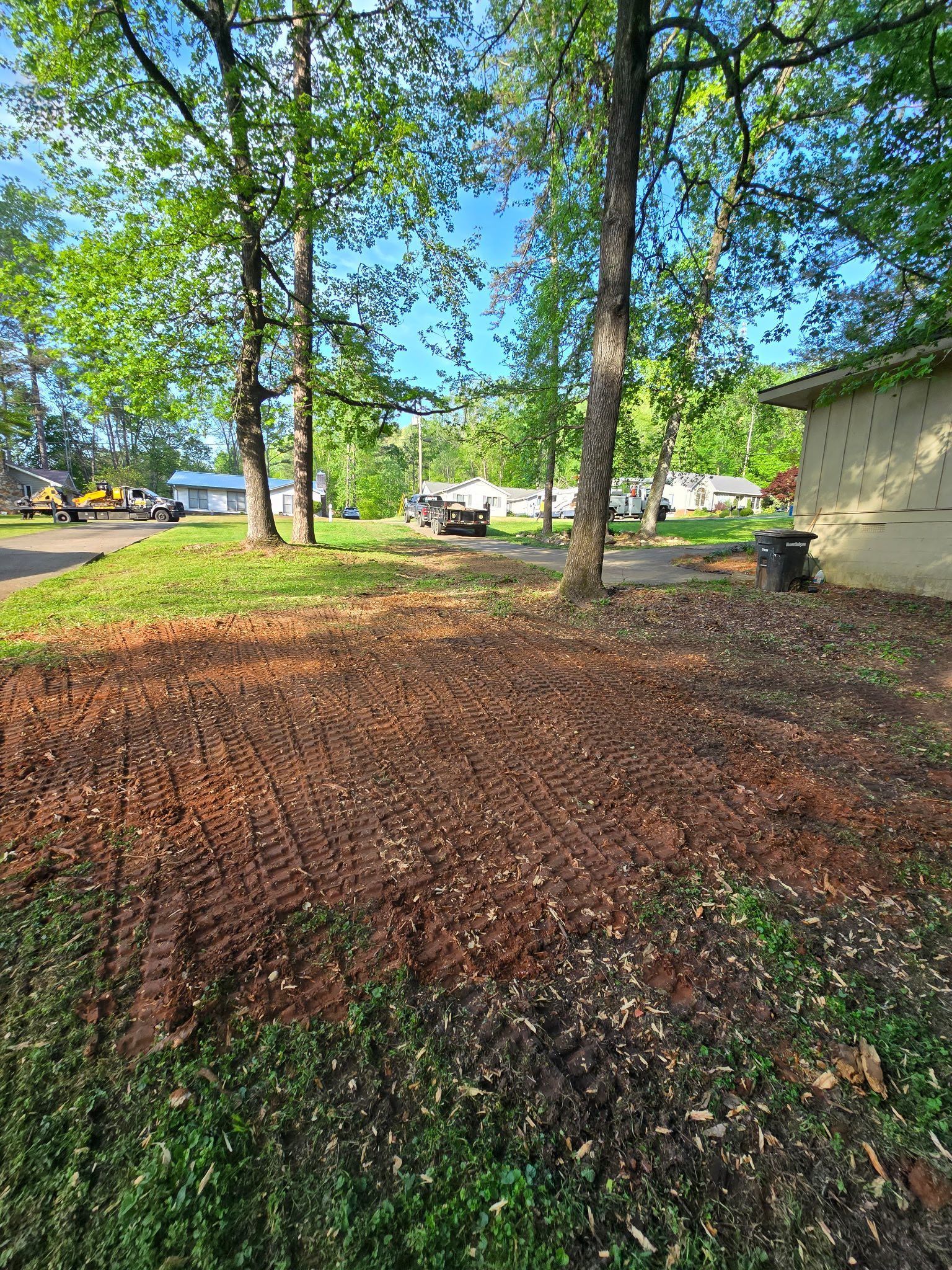 A yard with a lot of dirt and trees in the background.
