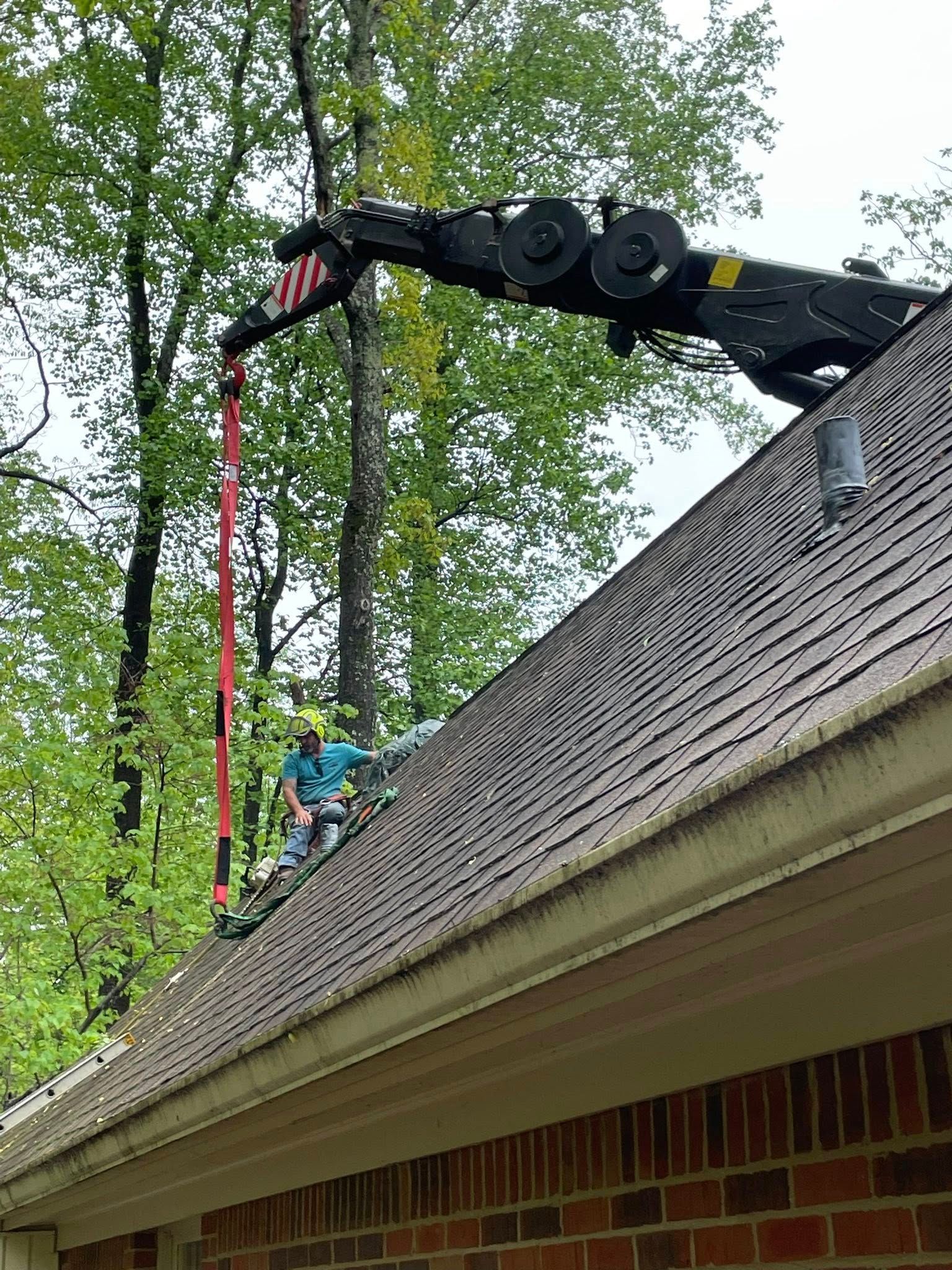 A man is sitting on top of a roof with a crane attached to it.