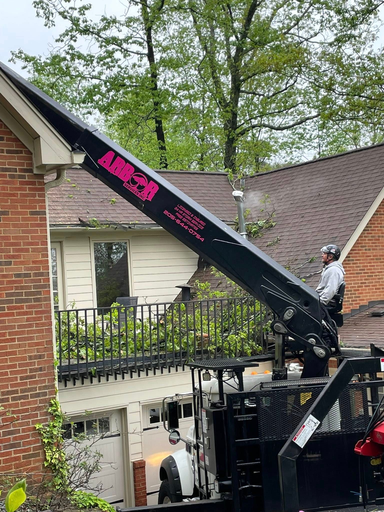 A man is standing on the roof of a house with a crane attached to it.