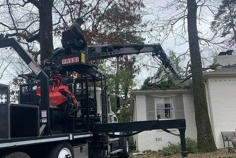 A truck with a crane attached to it is parked in front of a house.