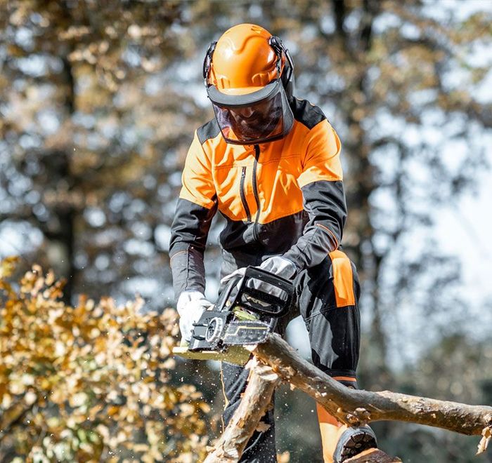 A man is cutting a tree branch with a chainsaw. A man is cutting a tree branch with a chainsaw.