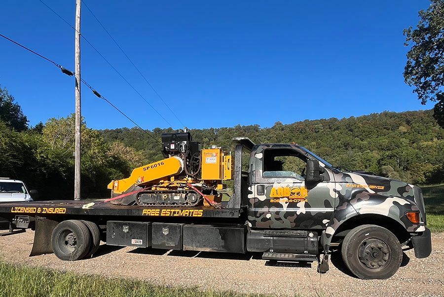 A tow truck with a tractor on the back is parked on the side of the road. A tow truck with a tractor on the back is parked on the side of the road.