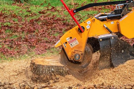 A stump grinder is grinding a tree stump in a yard.