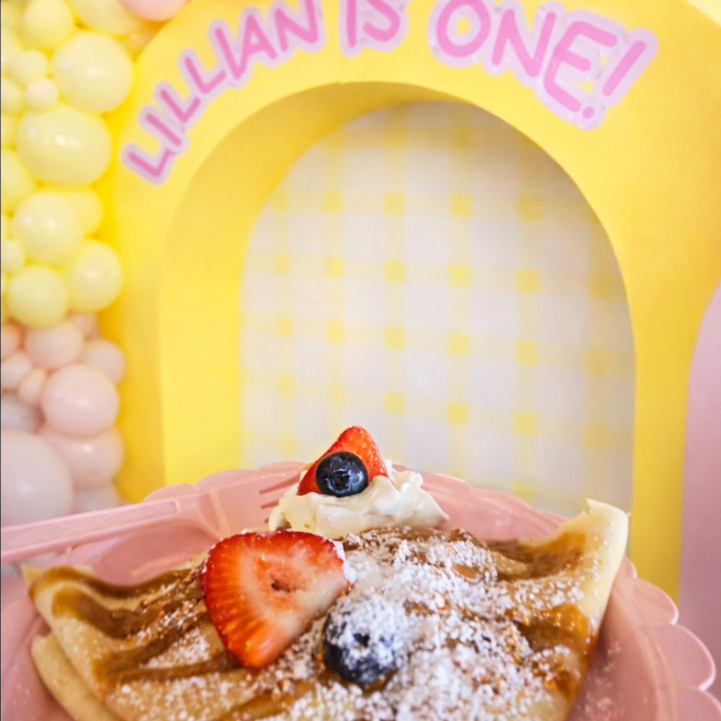 Cart decorated with red, gold, and black balloons, lit sign.