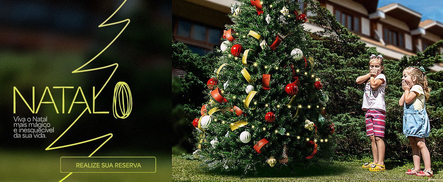 Duas crianças estão em frente a uma árvore de natal.