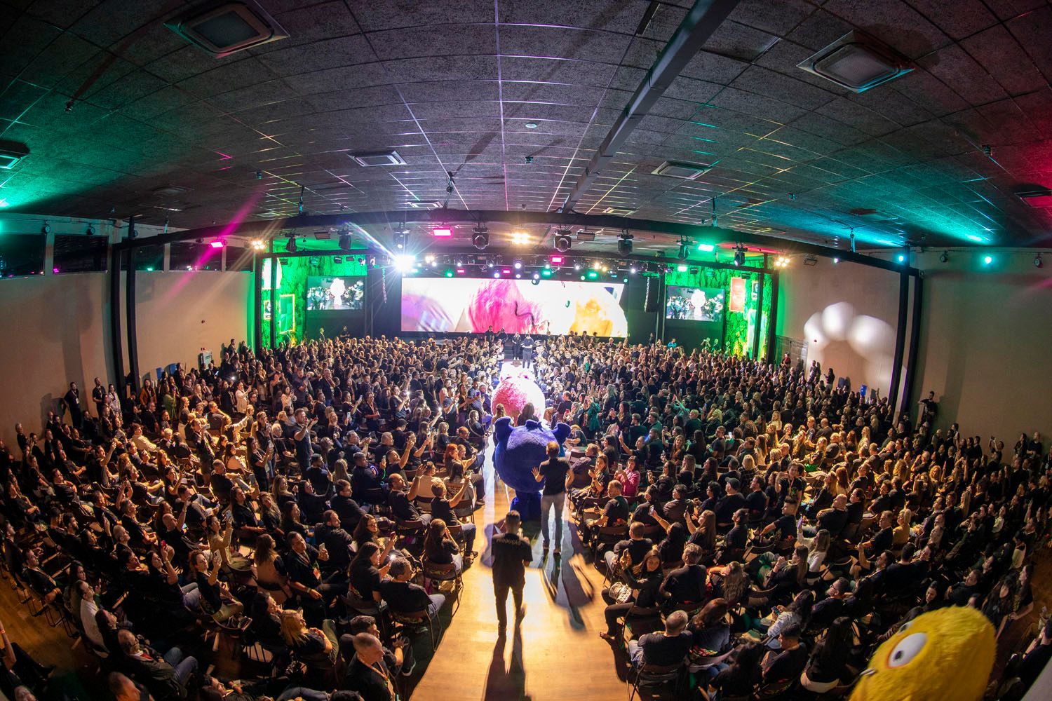 Um grande auditório cheio de pessoas assistindo a uma apresentação