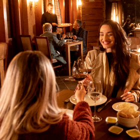 Um grupo de pessoas está sentado à mesa bebendo vinho