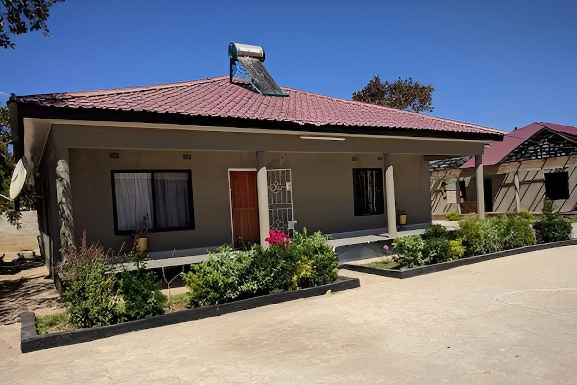 A one-story residential building with a tiled roof, solar heater, front porch, and manicured landscaping under a blue sky. — Daniher Building Company in Flynn, ACT