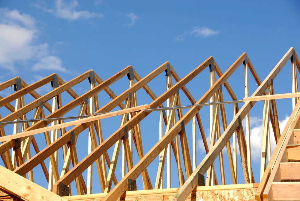 A Row of Wooden Roof Trusses Being Installed — Daniher Building Company in Flynn, ACT