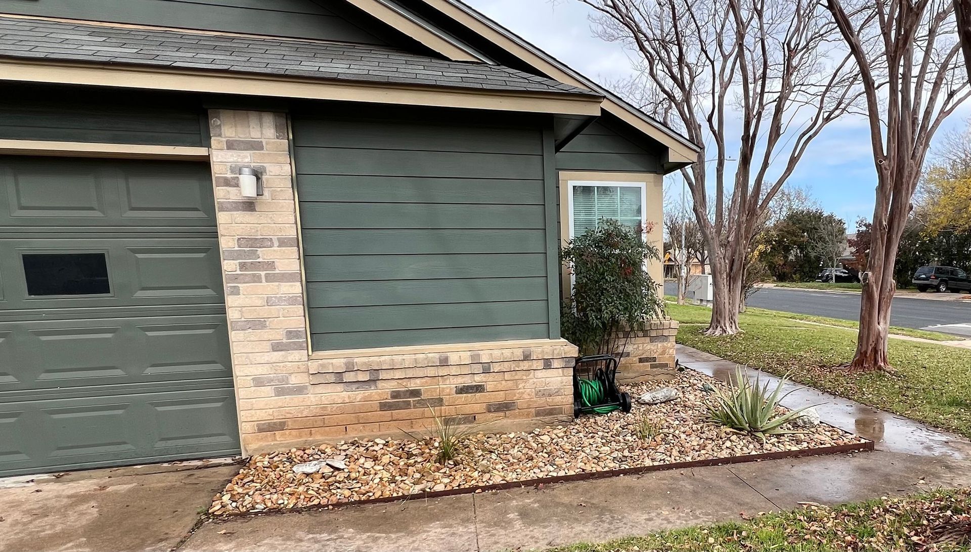 A house with a green garage door and a brick wall.