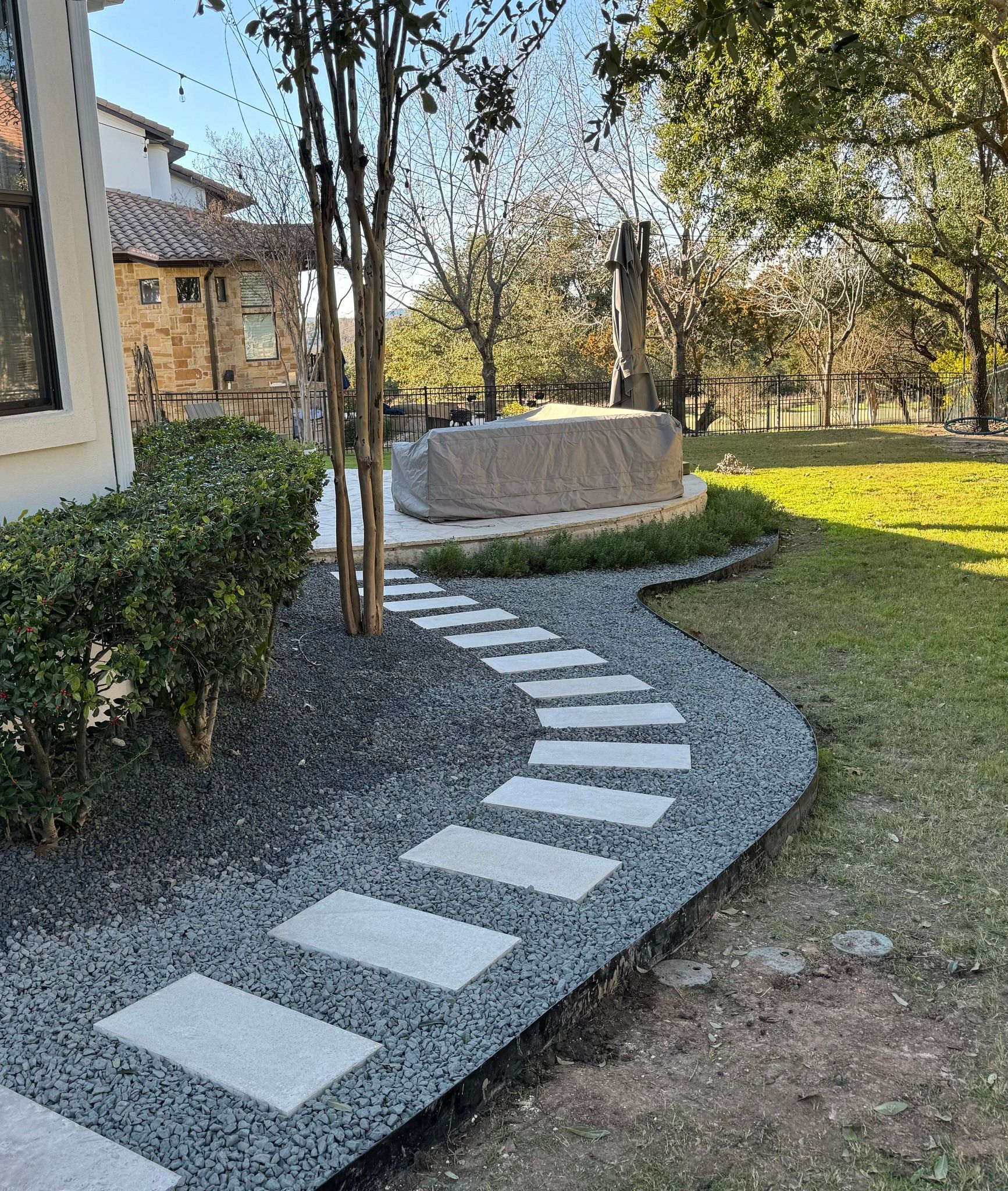 A stone walkway leading to a statue in a garden.