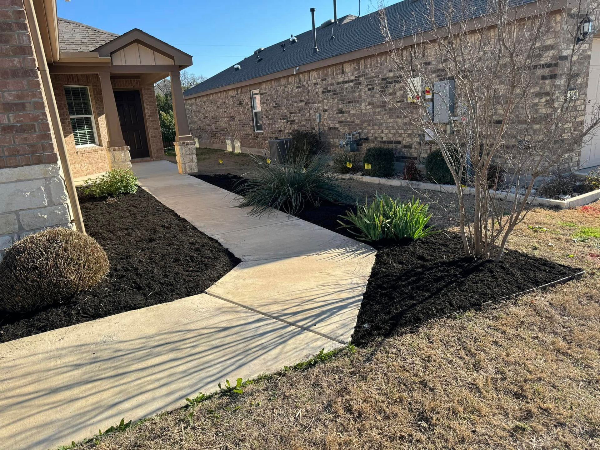A walkway leading to a house with a brick building in the background.