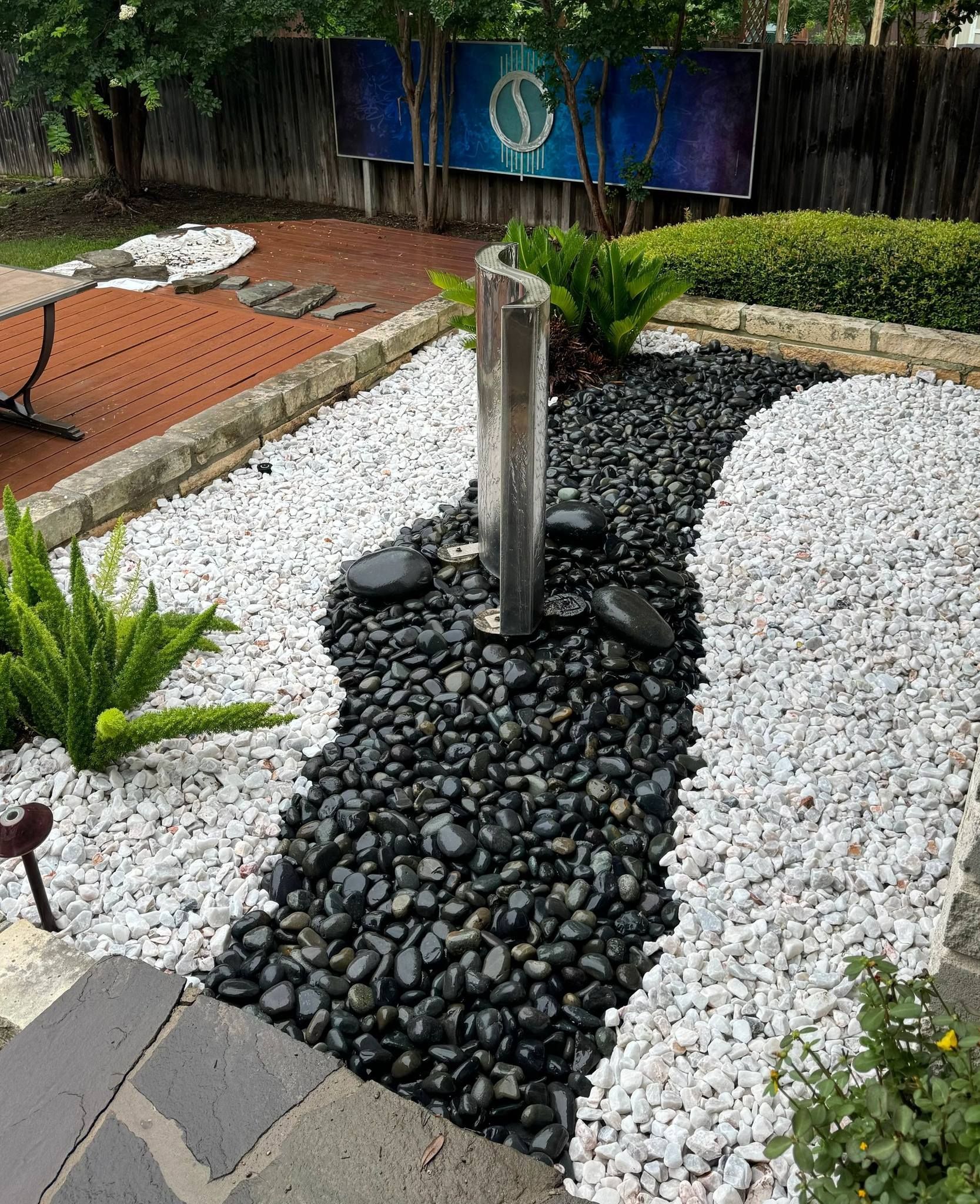 A garden with black and white rocks and a fountain in the middle.