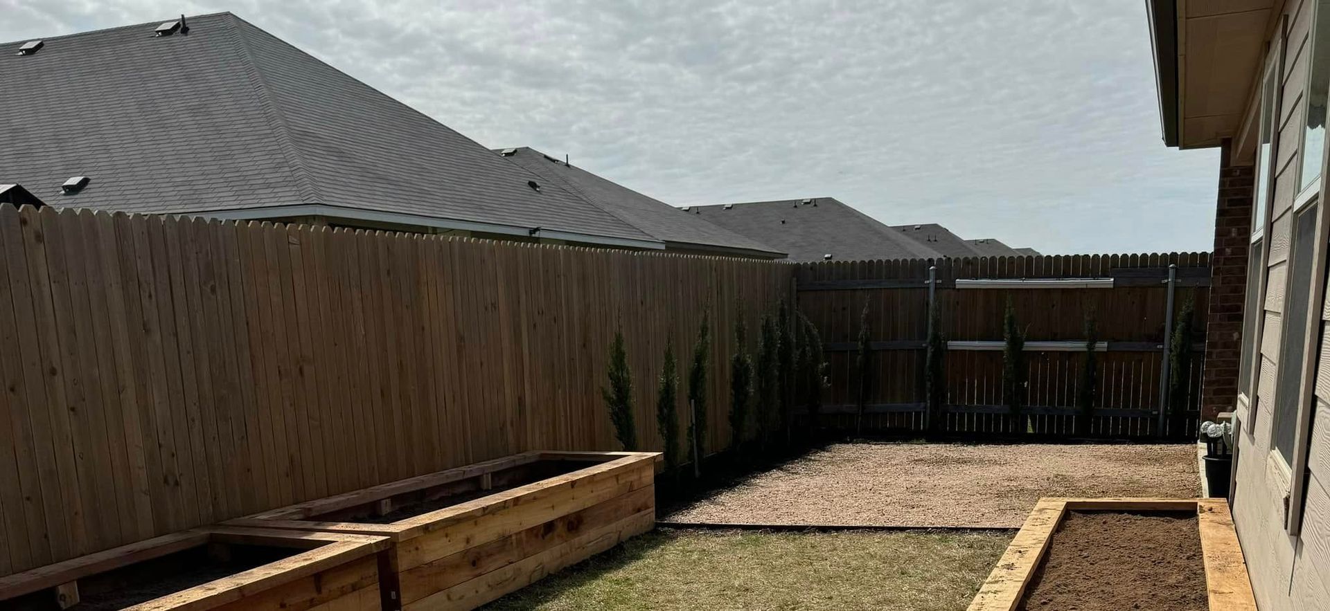 A backyard with a wooden fence and wooden planters.