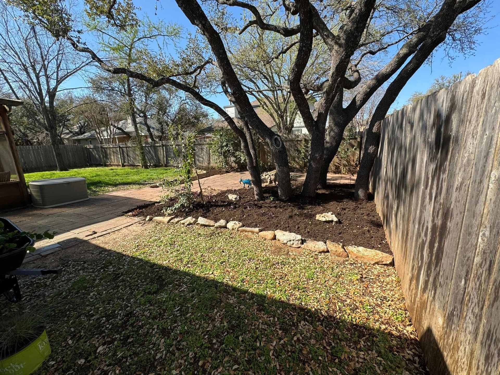 A backyard with a fence and trees in the background.