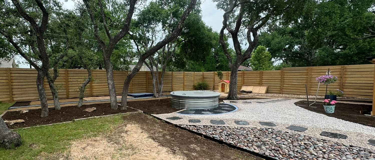 A backyard with a wooden fence and a fire pit.