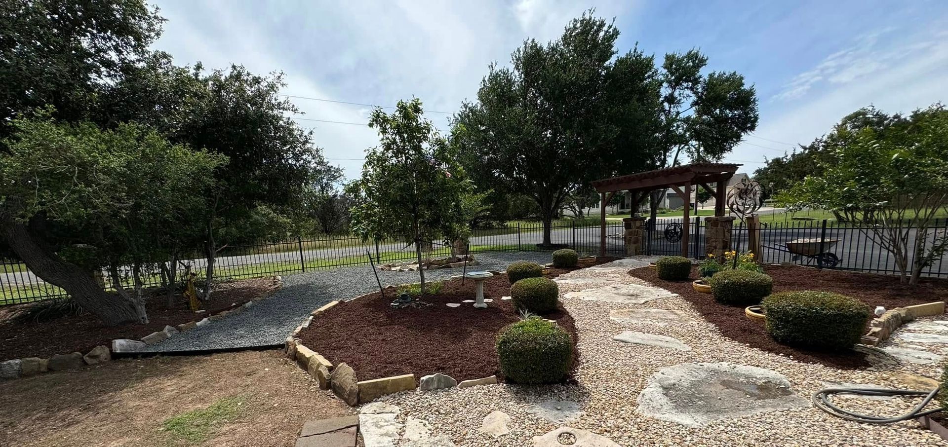 A path leading to a gazebo in a backyard surrounded by trees and bushes.
