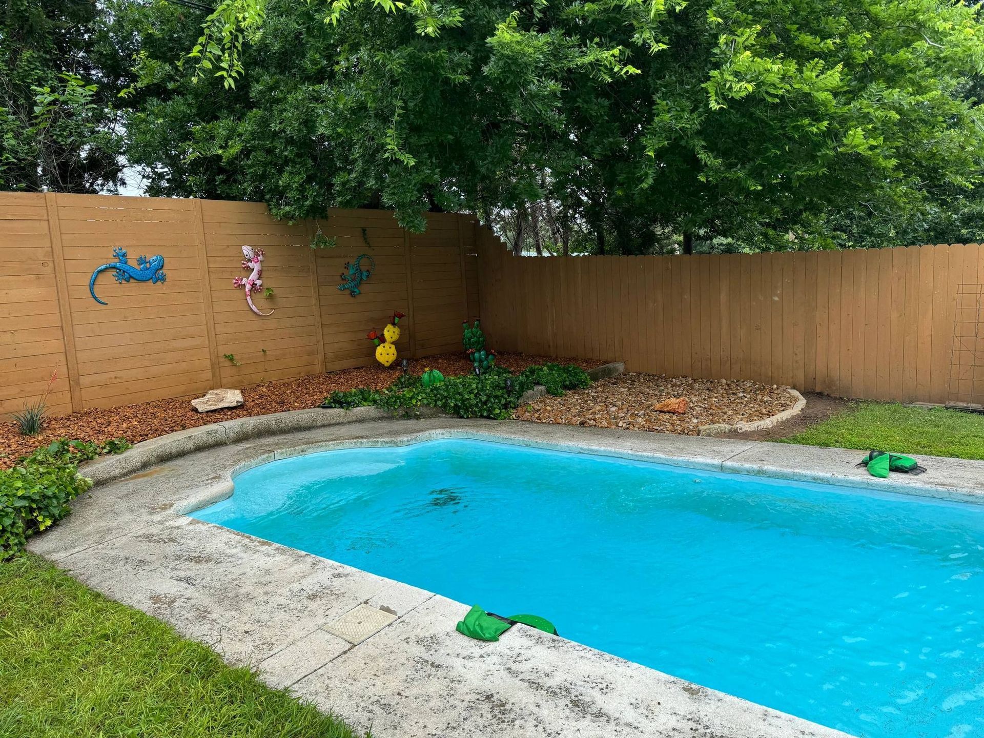 A swimming pool in a backyard with a wooden fence surrounding it.