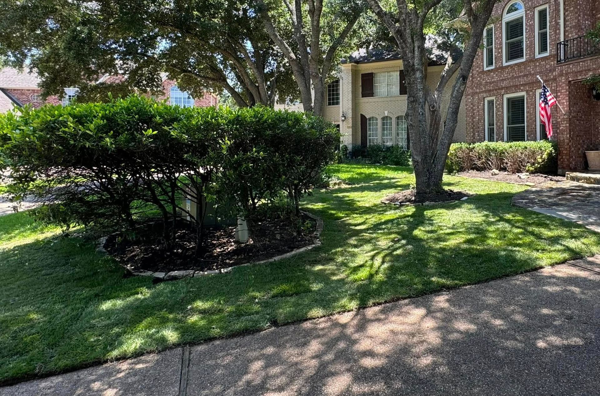 A large brick house with a lush green lawn and trees in front of it.