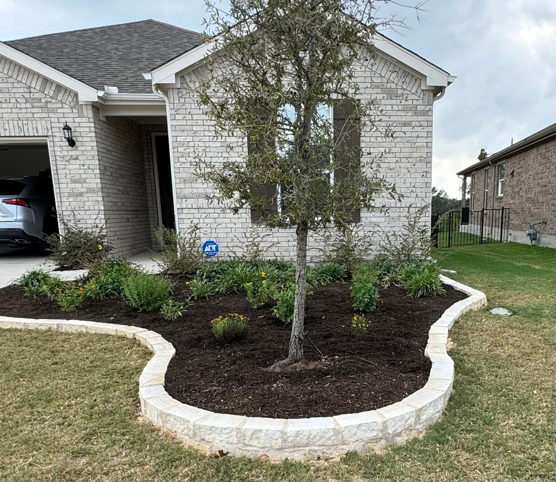A house with a tree in front of it and a car parked in the driveway.