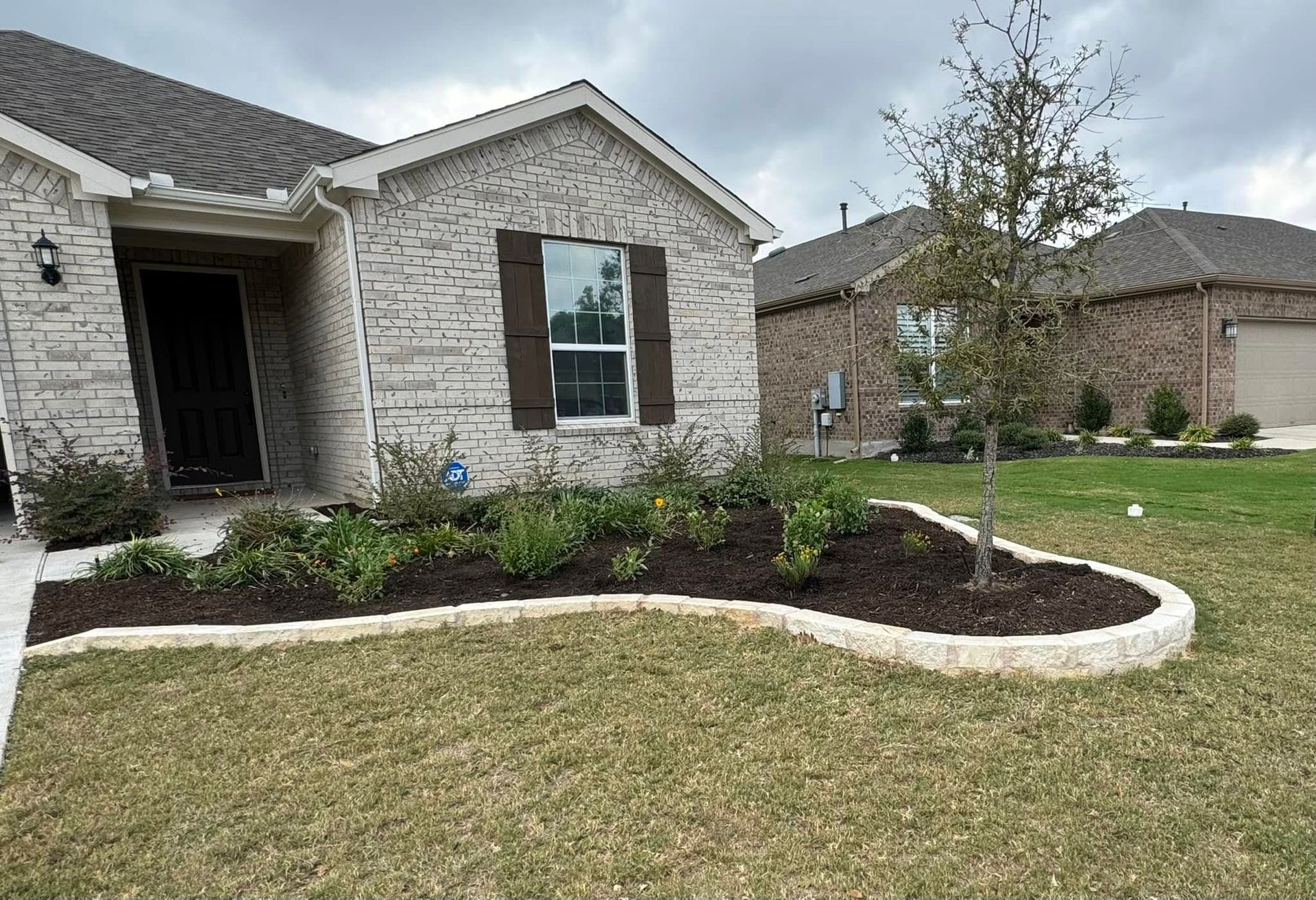 A brick house with a lush green lawn in front of it.