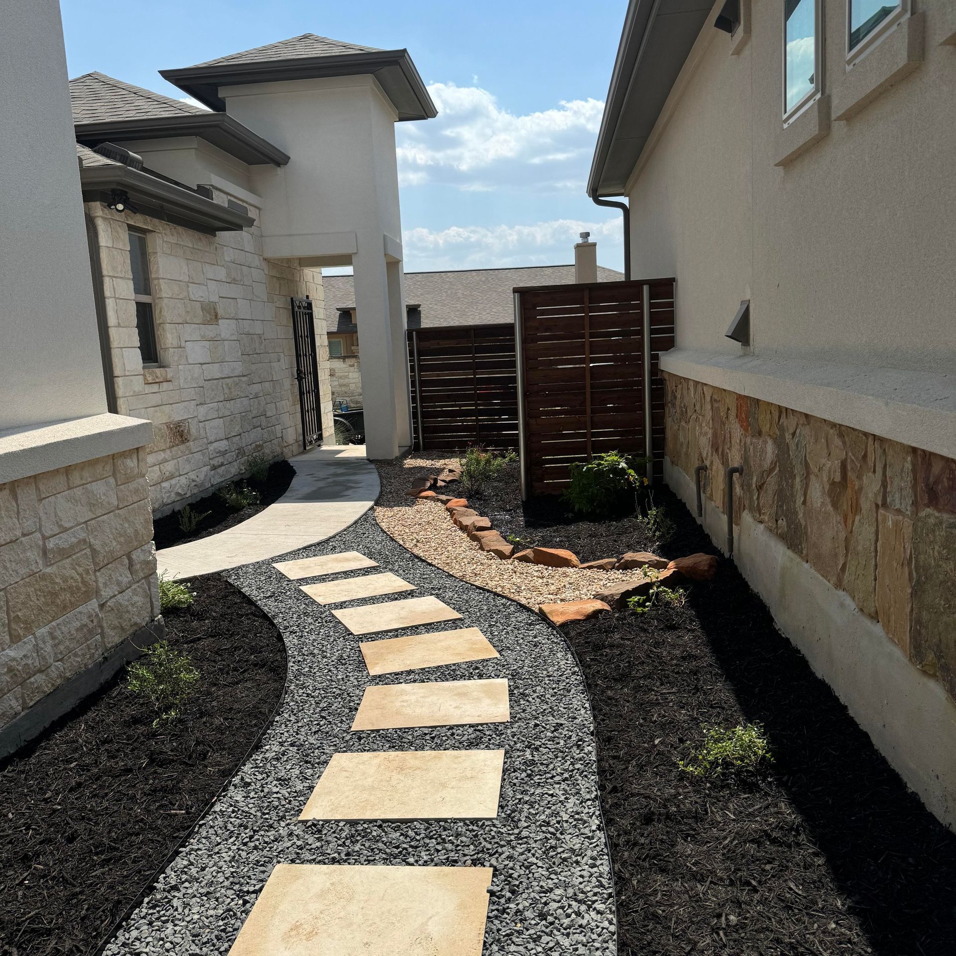 A stone walkway between two houses on a sunny day