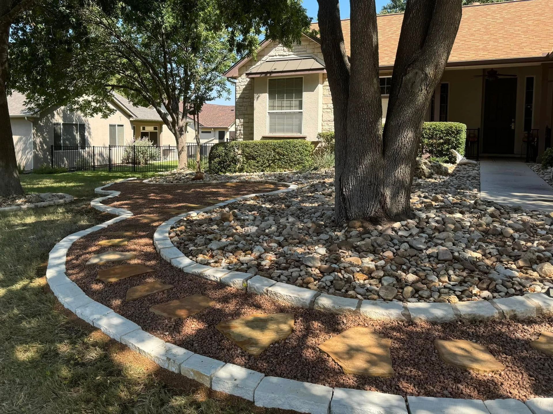 A tree is in the middle of a rock garden in front of a house.